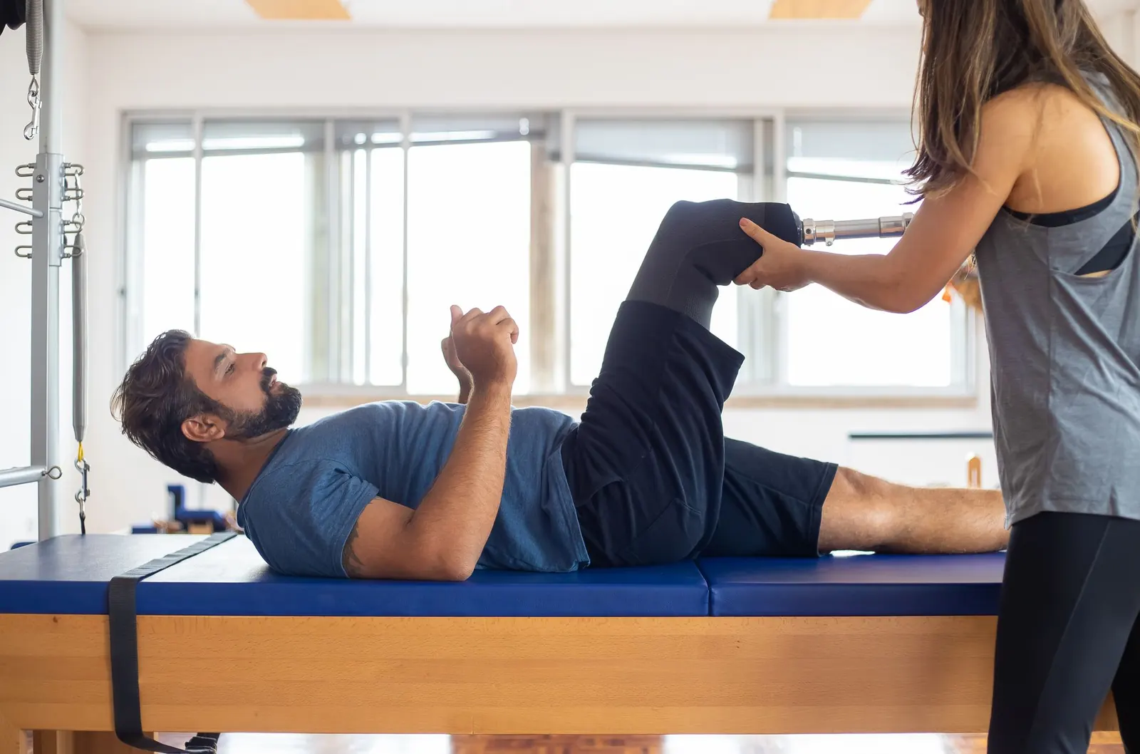 Therapist guiding a man's leg exercise on a rehab table in natural light