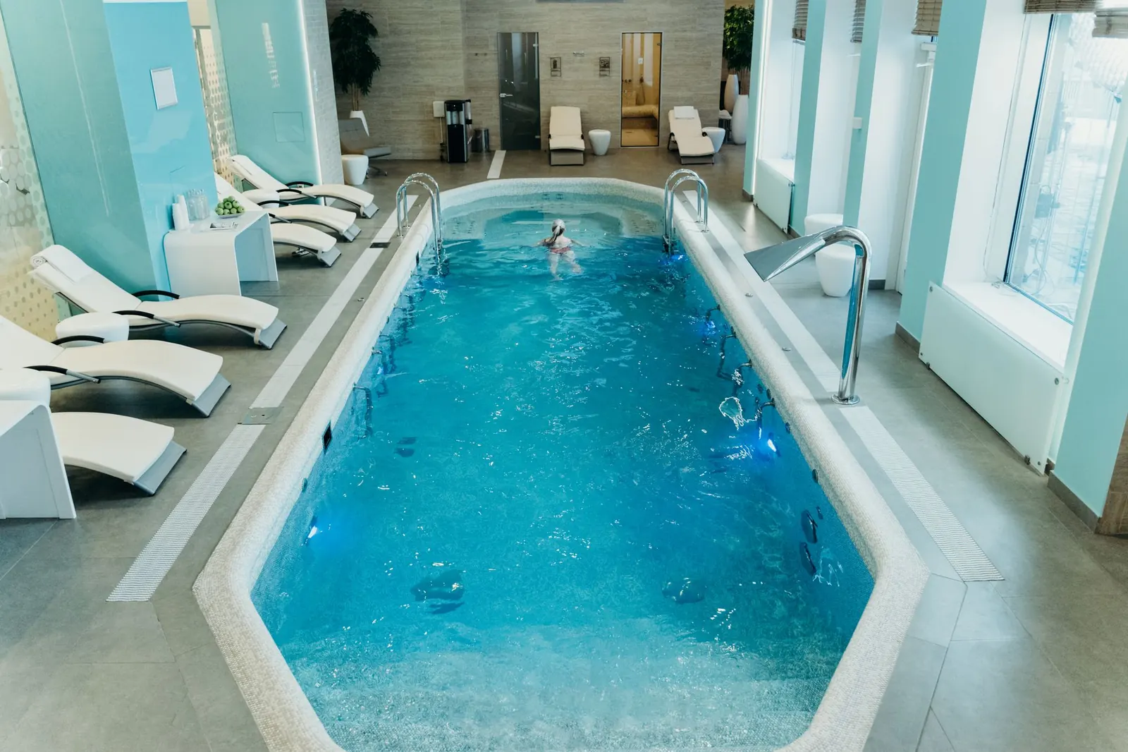 Indoor therapy pool with loungers in a bright, calm hall